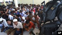 Seorang polisi berjaga saat pengungsi Rohingya tiba di tempat penampungan sementara di Lhoksukon, provinsi Aceh (13/5).