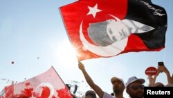 Demonstran mengibarkan bendera Turki dalam sebuah demonstrasi untuk menandai berakhirnya demonstrasi pemimpin utama partai Republikan People's Party (CHP) Kemal Kilicdaroglu selama 25 hari, yang dijuluki "Justice March", melawan penahanan anggota parlemen partai tersebut Enis Berberoglu, di Istanbul, Juli 9, 2017.
