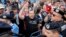 FILE - A protester shouts at riot police setting up fences during a protest outside the government headquarters in Bucharest, Romania, May 12, 2018.