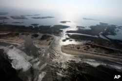 FILE - A flooded road on Hatteras Island, N.C., is shown after Hurricane Irene swept through the area, cutting the roadway in five locations, Aug. 28, 2011. Flooding caused by rising sea levels may end up costing U.S. coastal communities as much money and resources as major hurricane disasters, U.S. scientists said.