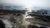 FILE - A flooded road on Hatteras Island, N.C., is shown after Hurricane Irene swept through the area, cutting the roadway in five locations, Aug. 28, 2011. Flooding caused by rising sea levels may end up costing U.S. coastal communities as much money and