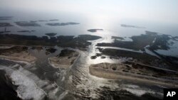 FILE - A flooded road on Hatteras Island, N.C., is shown after Hurricane Irene swept through the area, cutting the roadway in five locations, Aug. 28, 2011. Flooding caused by rising sea levels may end up costing U.S. coastal communities as much money and