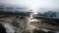 FILE - A flooded road on Hatteras Island, N.C., is shown after Hurricane Irene swept through the area, cutting the roadway in five locations, Aug. 28, 2011. Flooding caused by rising sea levels may end up costing U.S. coastal communities as much money and