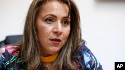 FILE - Helene Villalonga speaks during an interview at AMAVEX INC., an organization she founded that helps reunify migrant families and victims of domestic violence find shelter, in Doral, Fla., March 12, 2018. 