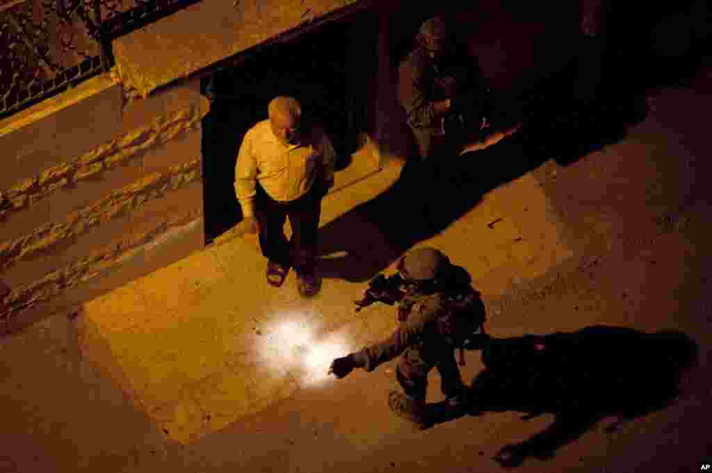 Israeli soldiers arrest Abdel Aziz Dweik, speaker of the long-defunct Palestinian parliament and a senior Hamas figure, at his home during a military operation to search for three missing Israeli teenagers, in the West Bank city of Hebron, June 16, 2014.