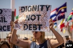 FILE - Activists hold placards during a demonstration against poverty and climate change on the first day of the annual meetings of the International Monetary Fund (IMF) and the World Bank Group (WBG), in Marrakesh on October 9, 2023.