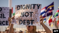 Des militants brandissent des pancartes lors d'une manifestation contre la pauvreté et le changement climatique au premier jour des réunions annuelles du Fonds monétaire international et du Groupe de la Banque mondiale, à Marrakech, le 9 octobre 2023.