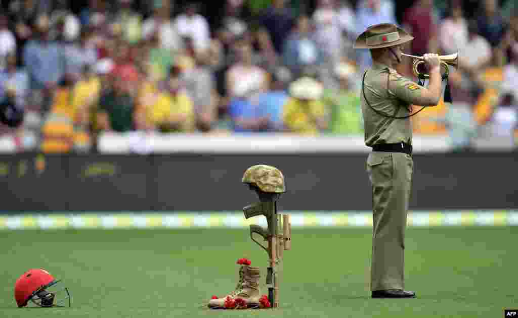 Seorang anggota tentara Australia memainkan terompet untuk memperingati 100 tahun pendaratan ANZAC pada tahun 1915 di Gallipoli sebelum hari pertama pertandingan uji coba kriket antara Australia dan New Zealand di Brisbane.