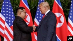 Rais wa Marekani Donald Trump akipeana mkono kwa mara ya kwanza na kiongozi wa Korea Kaskazini Kim Jong Un, katika hoteli ya Capella kwenye kiswa cha Sentosa, Singapore.