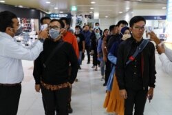 Petugas medis menggunakan termometer untuk mengecek suhu penumpang yang kebanyakan pekerja di stasiun Mass Rapid Transit (MRT), Jakarta, 5 Maret 2020. (Foto: REUTERS/Willy Kurniawan)