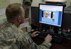 FILE - Army Staff Sgt. Matthew Millham, from New Paltz, N.Y., a former reporter for the military newspaper Stars and Stripes, checks the Facebook site in Kabul, Afghanistan, May 31, 2009.