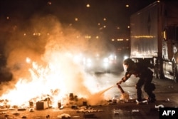 A police officer attempts to extinguish a fire on the I-85 (Interstate 85) during protests following the death of a man shot by a police officer on Sept. 21, 2016 in Charlotte, NC.