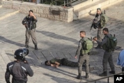 Israeli police stand around a Palestinian shot after he allegedly tried to stab a person at Damascus Gate of the Jerusalem's Old City, Oct. 14, 2015, Israeli police said.