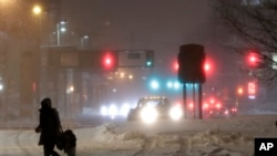 A woman and a child cross a snow-covered street during a snowstorm, Wednesday, March 21, 2018, in Jersey City, N.J. A spring nor'easter targeted the Northeast on Wednesday with strong winds and a foot or more of snow expected in some parts of the region.