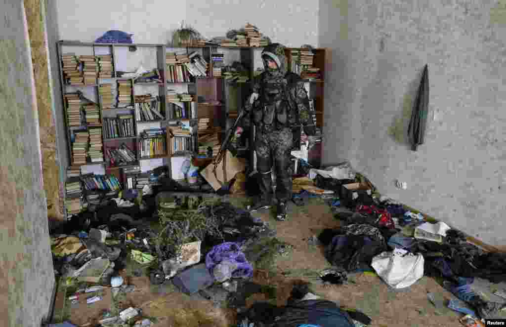 A pro-Russian separatist inspects a house where Ukrainian troops held one of their positions, in the town of Vuhlehirsk, eastern Ukraine, Feb. 10, 2015.