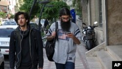 FILE - A man uses his cellphone while walking on a sidewalk in downtown Tehran, Iran, April 18, 2018.