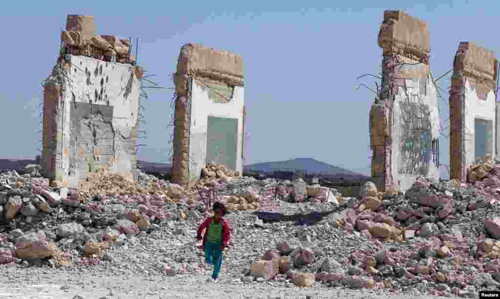 A girl runs near a damaged site in the Quneitra countryside, Syria.