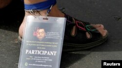 FILE - A Tibetan exile wears a badge on his ankle with a photo of former Chinese president Hu Jintao during a protest against Beijing's policies.