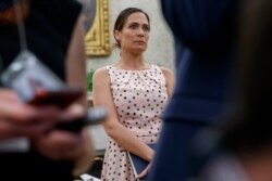 White House press secretary Stephanie Grisham, listens as President Donald Trump speaks with reporters on the South Lawn of the White House before departing, July 17, 2019, in Washington.