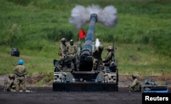 FILE - Japanese Ground Self-Defense Force soldiers fire a self-propelled howitzer during annual exercises near Mount Fuji at Higashifuji training field in Gotemba, west of Tokyo, Aug. 19, 2014.