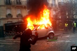 지난 1일 샹젤리제와 에투알 개선문 등 파리 최대 번화가에서 ‘노란 조끼’ 시위가 벌어진 가운데 시위자가 불 타는 차량 위로 물건을 던지고 있다.