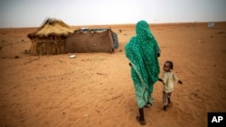 File photo released by the United Nations African Union Mission in Darfur (UNAMID), a woman holds hands with her daughter as they walk at the Zam Zam refugee camp for internally displaced people (IDP) in North Darfur, Sudan. 