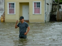 Barry Williams talks to a friend on his smartphone as he wades through storm surge from Lake Pontchartrain on Lakeshore Drive in Mandeville, La., as Hurricane Barry approached, July 13, 2019.