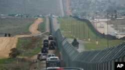 FILE - A motorcade carrying President Donald Trump drives along the border in San Diego, March 13, 2018.