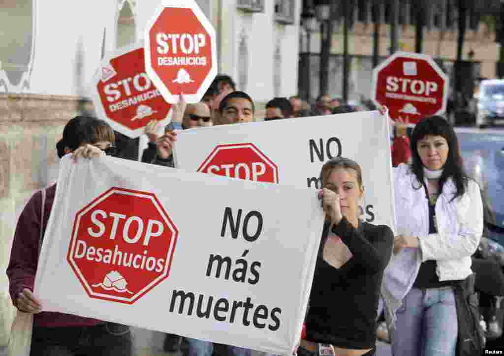 Members of the Mortgage Victims&#39; Platform shout slogans during a protest outside a Banesto Bank branch in Valencia, Spain. Banners and placards read, &quot;Stop evictions&quot; and &quot;No more dead people&quot;, which refers to suicides among some victims of home evictions due to non-payment.