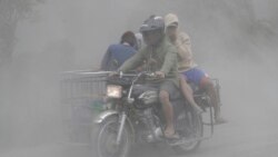 A family rides their motorcycle through clouds of ash as they evacuate to safer grounds as Taal volcano in Tagaytay, Cavite province, southern Philippines on Monday, Jan. 13, 2020. (AP Photo/Aaron Favila)