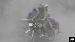 A family rides their motorcycle through clouds of ash as they evacuate to safer grounds as Taal volcano in Tagaytay, Cavite province, southern Philippines on Monday, Jan. 13, 2020. (AP Photo/Aaron Favila)