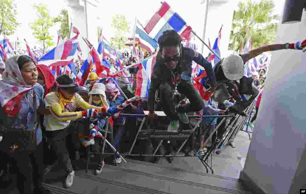 Anti-government protesters jump over the fence during a rally at the Department of Special Investigation on the outskirts of Bangkok, Dec. 23, 2013.