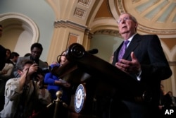 Senate Majority Leader Mitch McConnell of Ky., right, speaks to the media, July 24, 2018, on Capitol Hill in Washington.