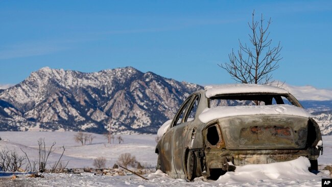 Snow covers the burned remains of a car after wildfires ravaged the area Sunday, Jan. 2, 2022, in Superior, Colo.