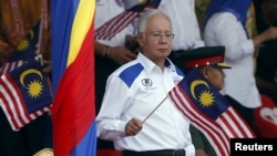 Perdana Menteri Malaysia Najib Razak melambaikan bendera nasional dalam perayaan hari kemerdekaan di Kuala Lumpur (31/8). (Reuters/Olivia Harris)