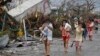 FILE - Residents cover their nose from the smell of dead bodies in Tacloban city, Leyte province central Philippines on Sunday, Nov. 10, 2013. 