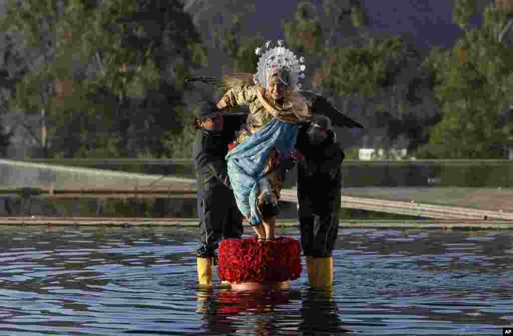 A woman wearing a costume of the Virgin Mary is helped by two men as part of the arrangements and actors welcoming the heads of state to the IV Summit of the Community of Latin American and Caribbean States, CELAC, in Quito, Ecuador.