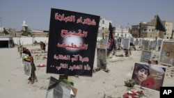 FILE- Religious flags, photographs and tributes to 21 victims of a suicide bombing, claimed by the Islamic State group, of a Shiite mosque are seen attached to their graves at a cemetery in Qudeeh, Saudi Arabia, May 30, 2015.