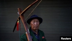 An ethnic Lisu man carries his crossbow as he poses for a photograph during a crossbow shooting competition in Luzhang township of Nujiang Lisu Autonomous Prefecture in Yunnan province, China, March 29, 2018. 
