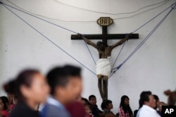 A crucifix, recovered from a collapsed church, is held up by ropes inside an auditorium during a Mass, in Tepeojuma, Mexico, Sept. 24, 2017.