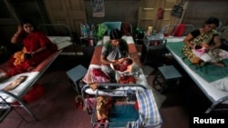 FILE - Mothers hold their newborn babies as they rest inside a maternity hospital, in Kolkata, July 11, 2012.
