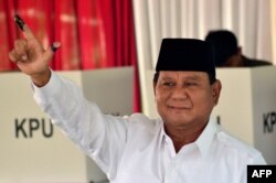 Presidential challenger Prabowo Subianto shows off his ink-dyed finger after casting his vote in Indonesia's general election at a polling station in Bogor, April 17, 2019.