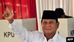 Presidential challenger Prabowo Subianto shows off his ink-dyed finger after casting his vote in Indonesia's general election at a polling station..