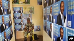 A soldier sits amidst election posters of Presidential candidate Alpha Conde in the entrance of the Guinean People Rally (RPG) headquarters in Guinea's capital Conakry Saturday 18 Sept. 2010.