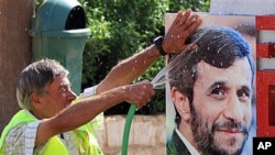 A Lebanese worker washes a portrait of Iranian President Mahmoud Ahmadinejad, at a border park in the village of Maroun el-Rass on the Lebanon-Israel border, Lebanon, 4 Oct 2010