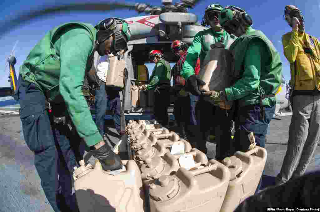 Sailors aboard the U.S. Navy&#39;s forward-deployed aircraft carrier USS George Washington load containers of water onto an MH-60S Seahawk, Nov. 15, 2013. (U.S. Navy)