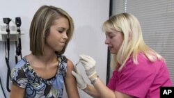 Une jeune demoiselle se fait administrer un vaccin.