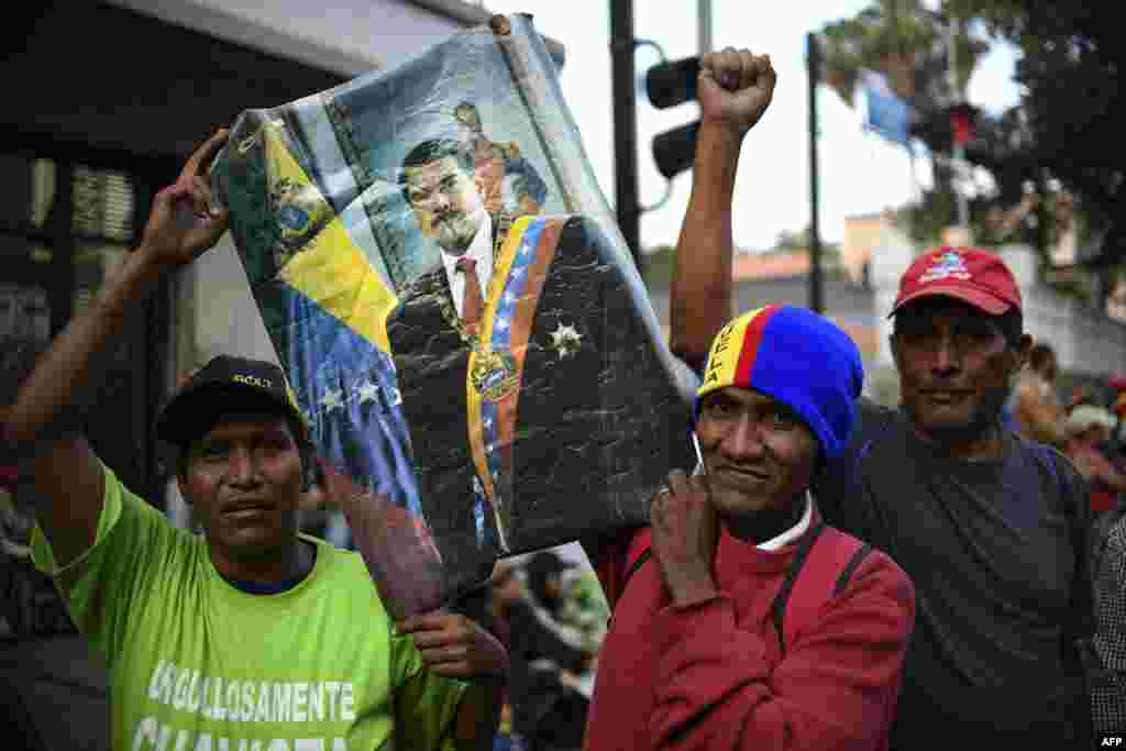 Supporters of the Venezuela's President Nicolas Maduro who stay on vigil in front of the Presidential Palace of Miraflores pose with a poster in Caracas, Venezuela, May 1, 2019.