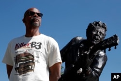 Charles Berry Jr., son of rock 'n' roll legend Chuck Berry, poses alongside a statue of his late father, in University City, Missouri, May 31, 2017.