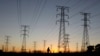 FILE - A man walks past electricity pylons as he returns from work in Soweto, outside Johannesburg, May 15, 2012. 